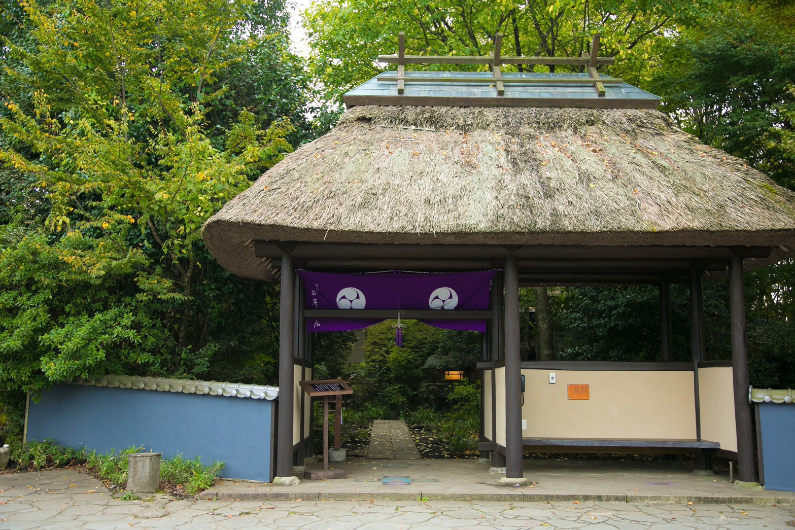 茅葺き屋根の門と紫の暖簾